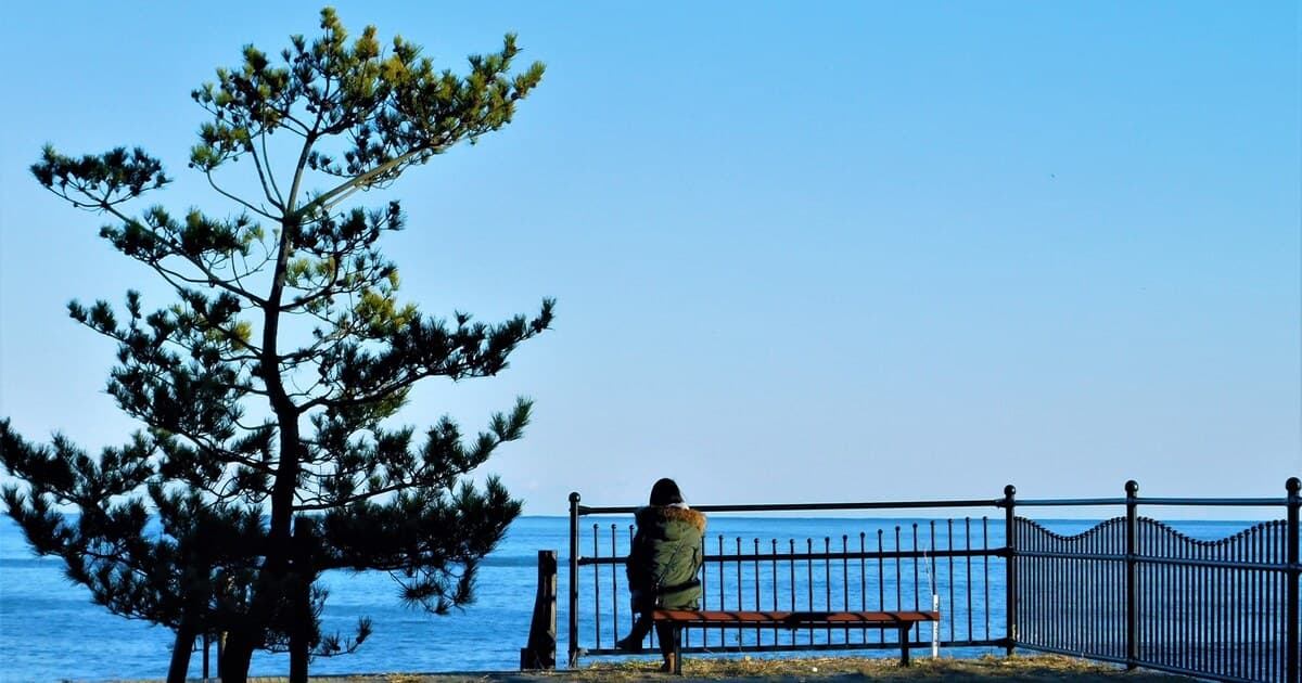 海辺のベンチで一人過ごす人