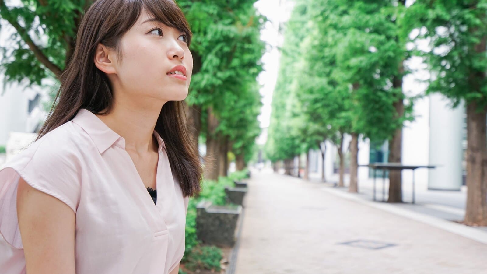 緑の並木道で一人で考え込む女性