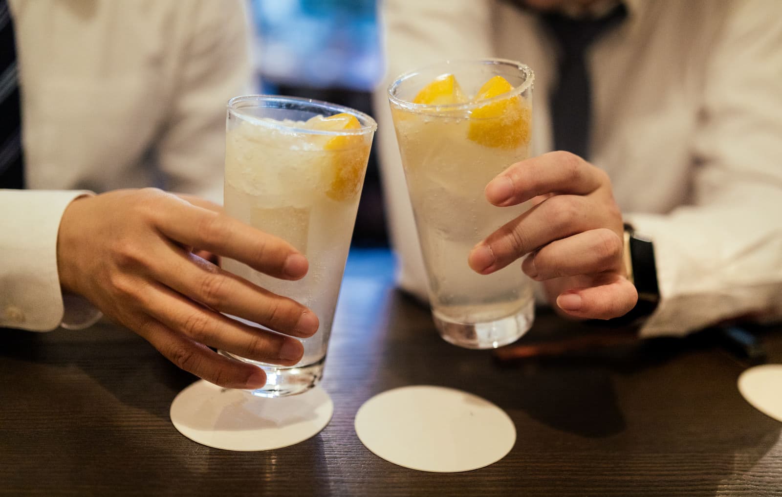 居酒屋でレモンサワーを持って乾杯する手元