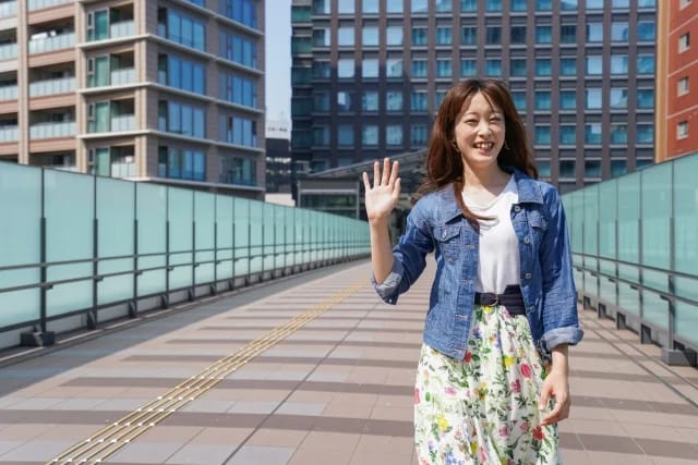 屋外の歩道で笑顔で手を振る女性