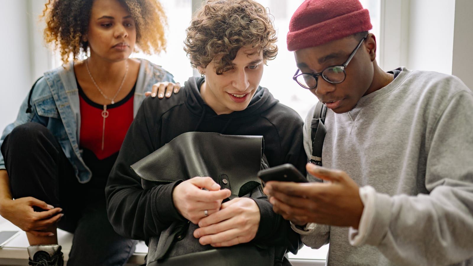 スマートフォンを囲み、オンラインの話題でつながる若者たち