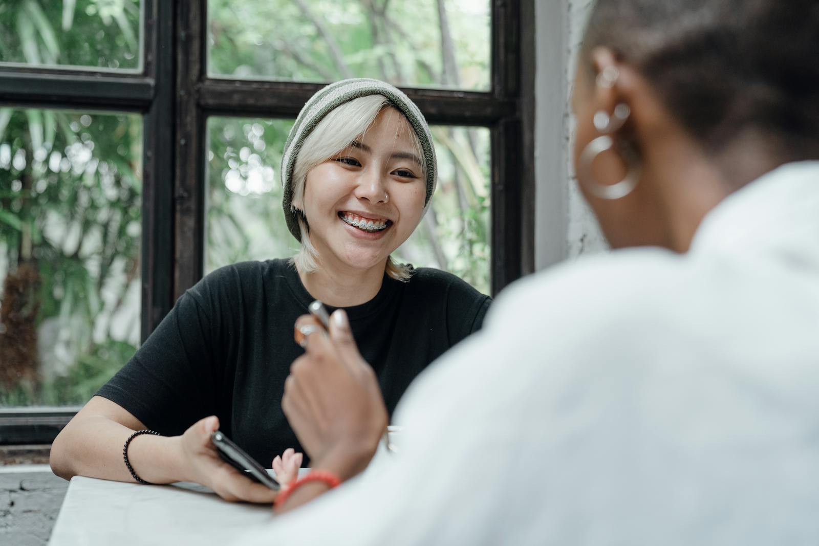 カフェでスマートフォンを見ながら会話する女性たち