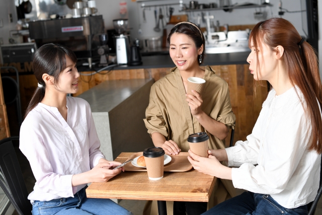 昼間のカフェで会話する3人の女性