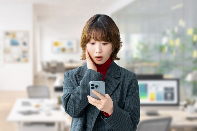 不審なメッセージを見て驚く女性